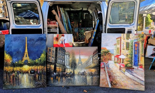 art and paintings displayed in front of a open vehicle